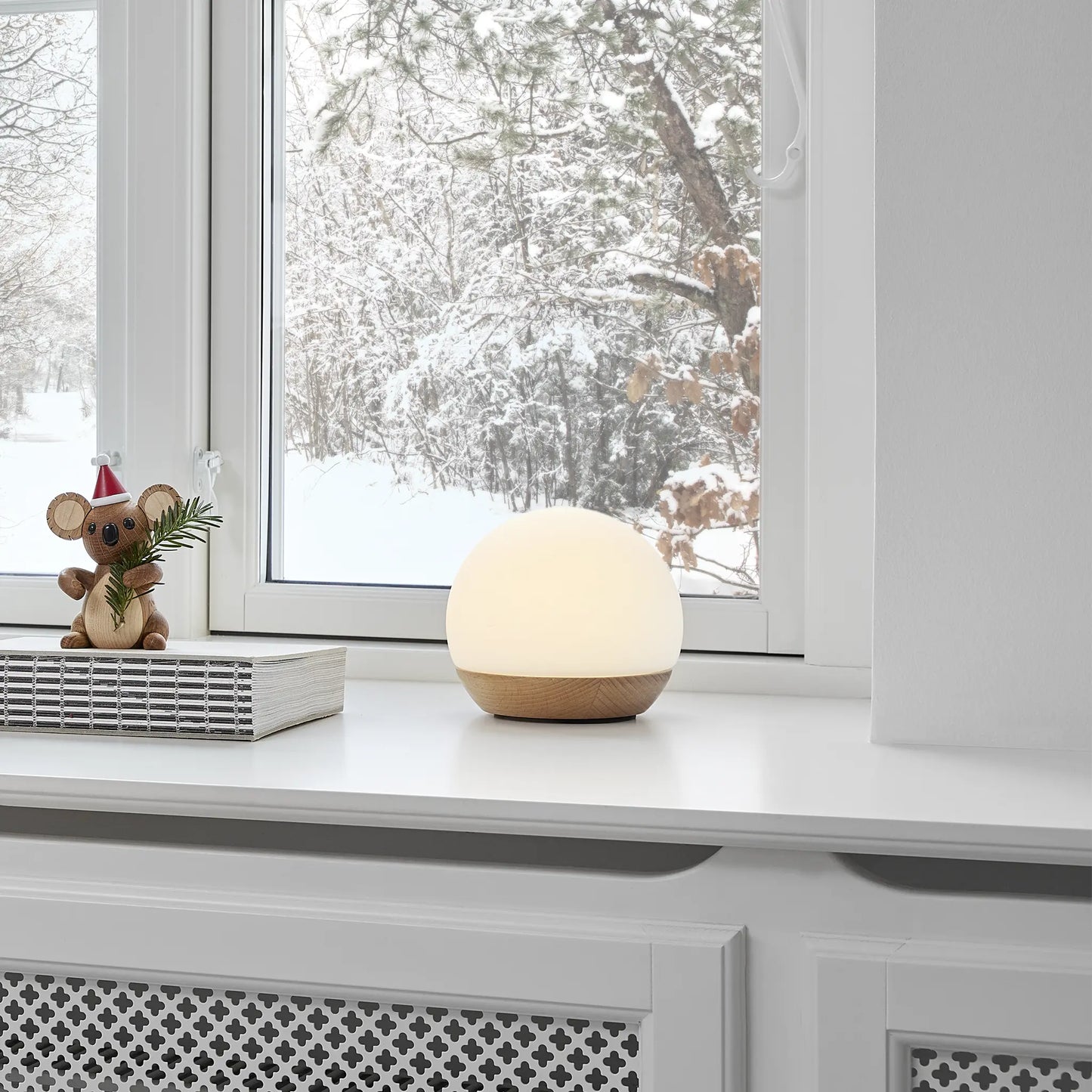 Bordlampan Spring Snowball designad av mencke&vagnby stående på en fönsterkarm