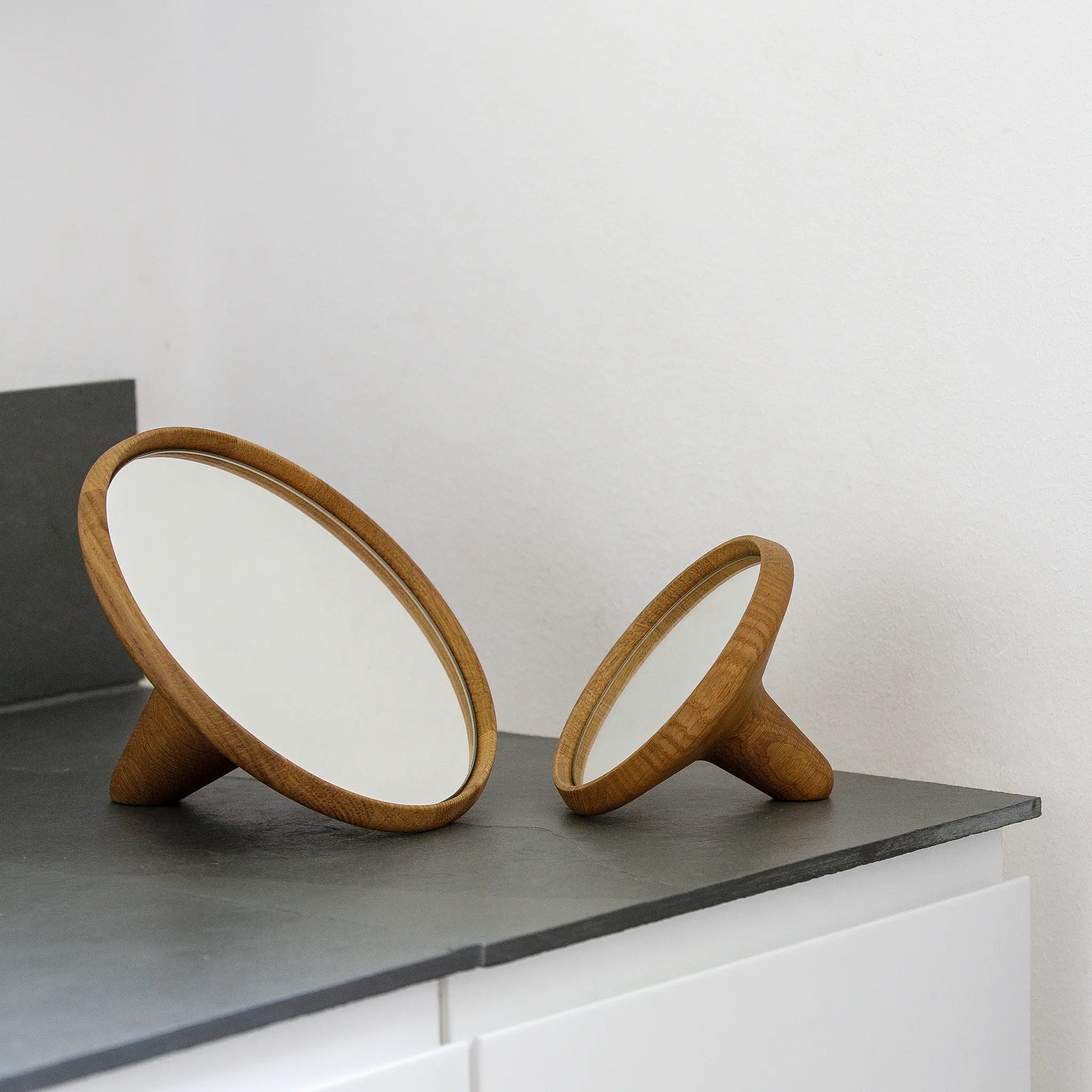 Satellite Mirror speglar i ekträ på en grå bänk i badrummet