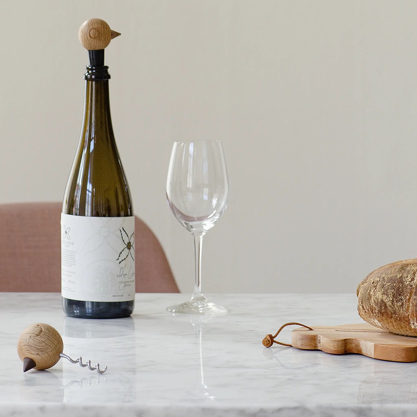 Bilden visar Tipsy korkskruv och vinkork av FaPrik på ett bord med ett glas och vinflaska